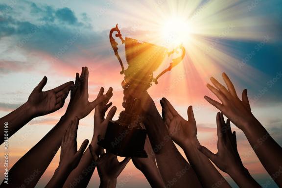People reaching for a trophy